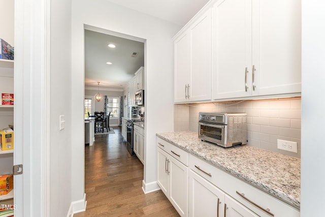 kitchen featuring light stone countertops, backsplash, wood-type flooring, white cabinets, and appliances with stainless steel finishes