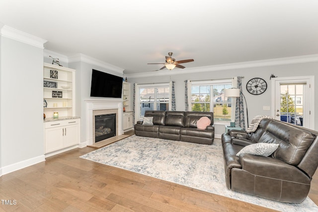 living room with crown molding, plenty of natural light, and light wood-type flooring