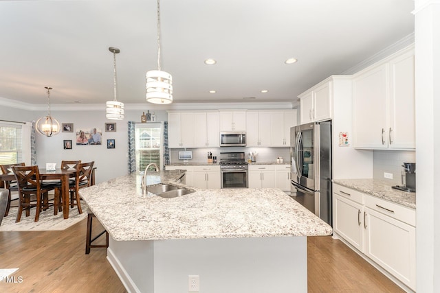 kitchen featuring hanging light fixtures, sink, stainless steel appliances, and a large island with sink