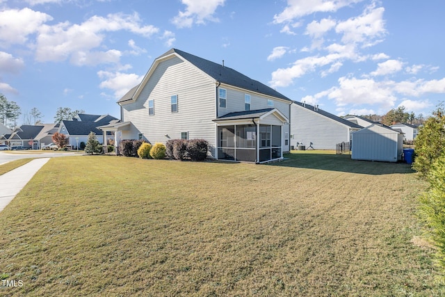 rear view of house featuring a sunroom, a yard, and a storage shed