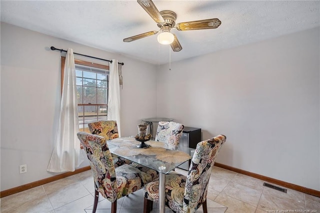 tiled dining room with ceiling fan and a textured ceiling