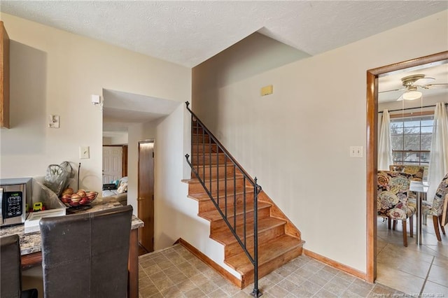 stairs with tile patterned floors, ceiling fan, and a textured ceiling