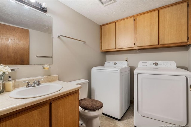 clothes washing area with a textured ceiling, separate washer and dryer, and sink