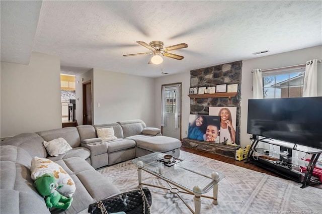 living room with ceiling fan, wood-type flooring, and a textured ceiling