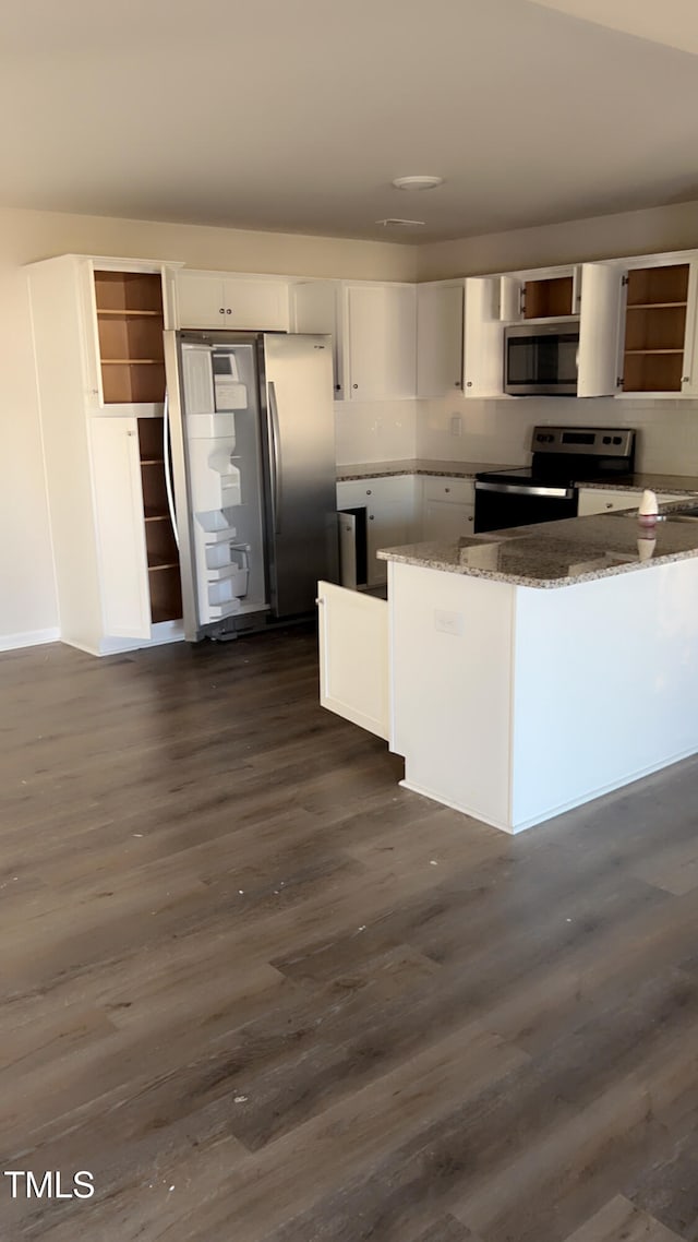 kitchen featuring stone counters, stainless steel appliances, white cabinetry, and dark wood-type flooring