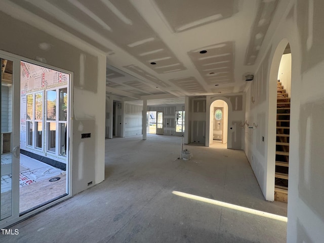 spare room featuring arched walkways, stairway, and a healthy amount of sunlight