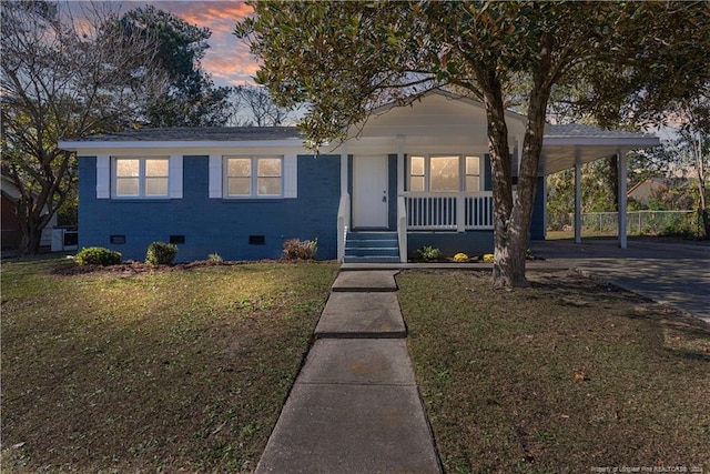 view of front of house featuring a lawn, covered porch, and a carport