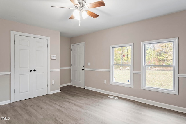 empty room with ceiling fan and light hardwood / wood-style floors