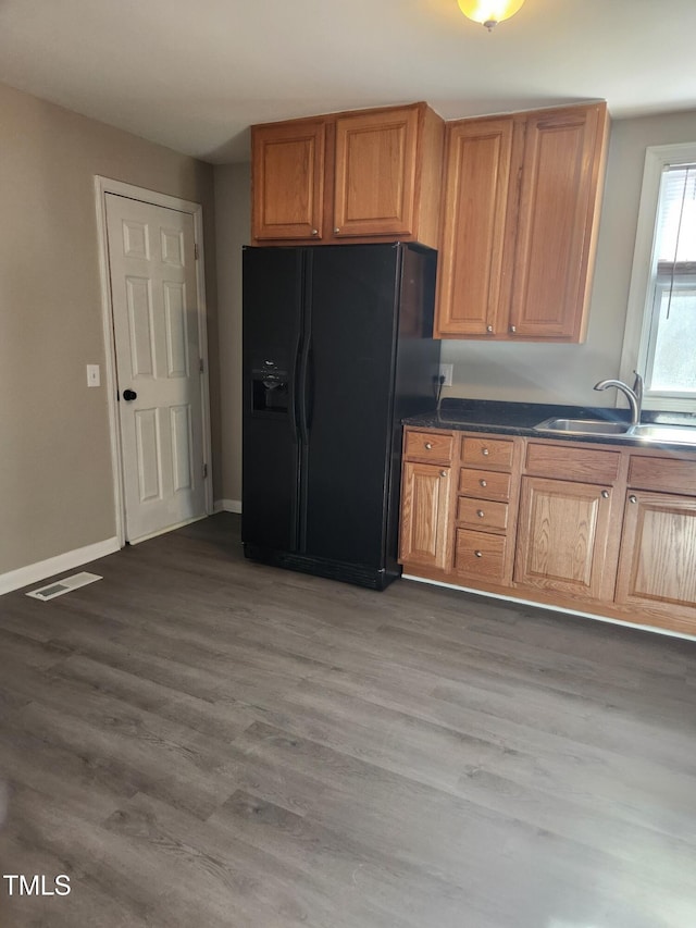 kitchen featuring wood-type flooring, black fridge with ice dispenser, and sink