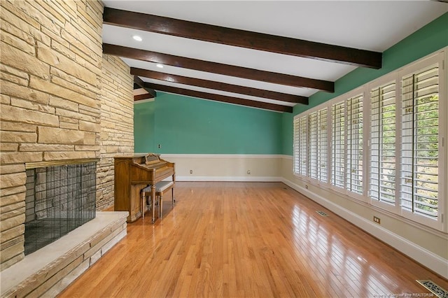 unfurnished living room featuring beamed ceiling, light wood-type flooring, and a fireplace