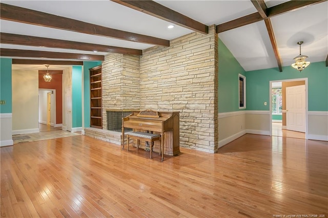 unfurnished living room featuring beam ceiling, built in features, a notable chandelier, and hardwood / wood-style floors