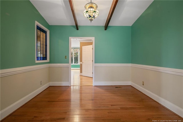 empty room featuring lofted ceiling with beams and light hardwood / wood-style flooring