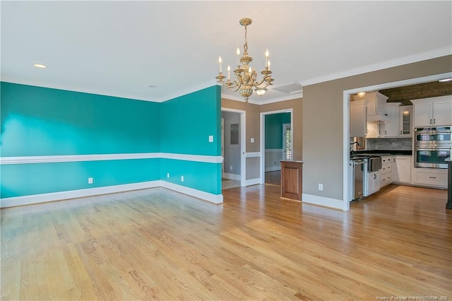 interior space with light hardwood / wood-style flooring, an inviting chandelier, and ornamental molding