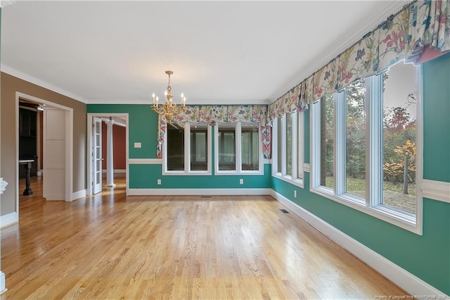 interior space featuring hardwood / wood-style flooring, an inviting chandelier, a wealth of natural light, and ornamental molding