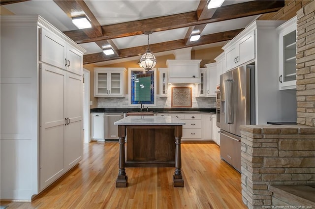 kitchen with decorative backsplash, a kitchen island, decorative light fixtures, and appliances with stainless steel finishes