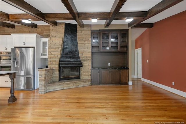 interior space featuring light hardwood / wood-style floors, high end fridge, white cabinetry, and beamed ceiling