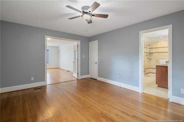 unfurnished bedroom featuring french doors, light wood-type flooring, ensuite bathroom, and ceiling fan