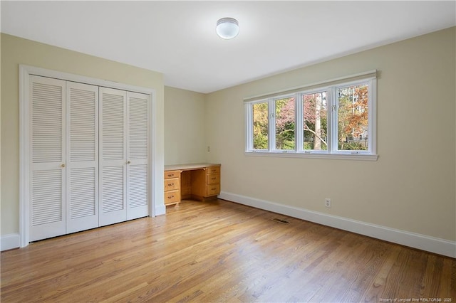 unfurnished bedroom featuring light wood-type flooring and a closet