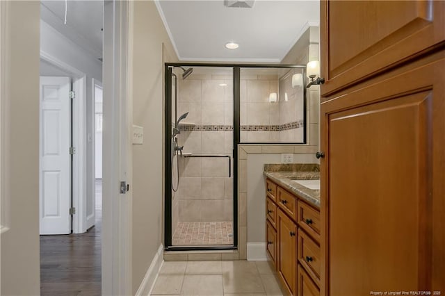 bathroom with tile patterned flooring, vanity, a shower with door, and ornamental molding