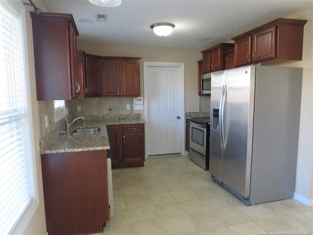 kitchen with decorative backsplash, stainless steel appliances, light stone counters, and sink