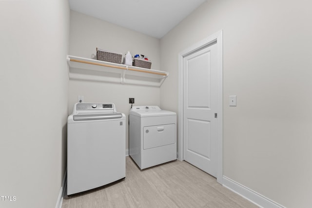 laundry area with washing machine and dryer and light wood-type flooring