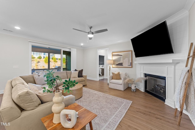 living room featuring hardwood / wood-style floors, ceiling fan, and ornamental molding