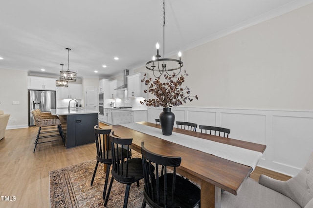 dining room featuring a notable chandelier, light hardwood / wood-style floors, and crown molding