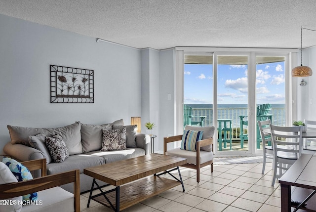 living room featuring light tile patterned floors, a water view, a textured ceiling, and a wall of windows