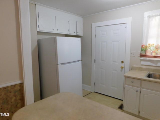 kitchen featuring white cabinets, white fridge, and ornamental molding