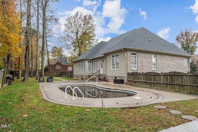 rear view of property with a yard and an empty pool