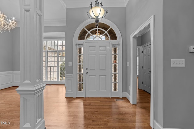 entryway with hardwood / wood-style floors, ornamental molding, and decorative columns