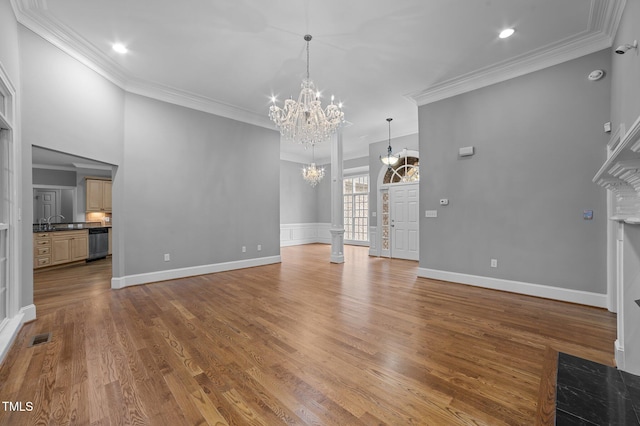 unfurnished living room with sink, wood-type flooring, and ornamental molding