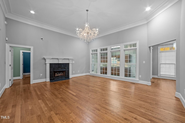 unfurnished living room with a tile fireplace, crown molding, a towering ceiling, a chandelier, and light hardwood / wood-style floors