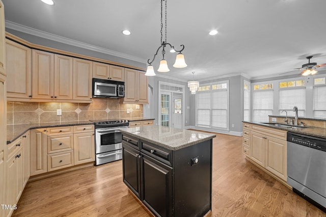 kitchen featuring light wood-type flooring, a wealth of natural light, stainless steel appliances, sink, and hanging light fixtures