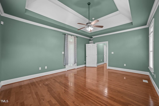 spare room with wood-type flooring, a tray ceiling, and a wealth of natural light