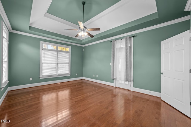 empty room featuring a tray ceiling, crown molding, ceiling fan, and wood-type flooring