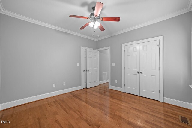 unfurnished bedroom with ceiling fan, light hardwood / wood-style floors, crown molding, and a closet