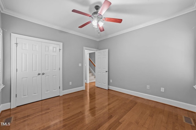 unfurnished bedroom featuring a closet, hardwood / wood-style flooring, ceiling fan, and ornamental molding