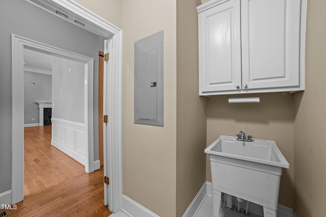 washroom with sink, electric panel, and light hardwood / wood-style flooring