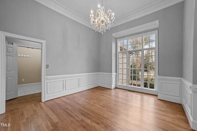 unfurnished dining area featuring light hardwood / wood-style floors, ornamental molding, and an inviting chandelier