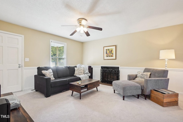 living room featuring a textured ceiling, ceiling fan, and light carpet