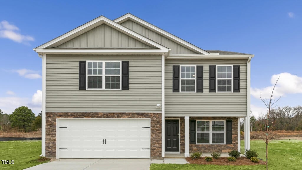 craftsman inspired home featuring a garage and a front lawn