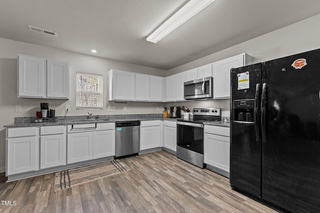 kitchen with white cabinetry, sink, stainless steel appliances, and light hardwood / wood-style floors