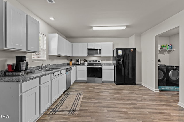 kitchen with separate washer and dryer, stainless steel appliances, white cabinets, and sink