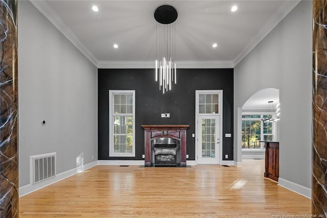 unfurnished living room with light hardwood / wood-style flooring, crown molding, and a notable chandelier