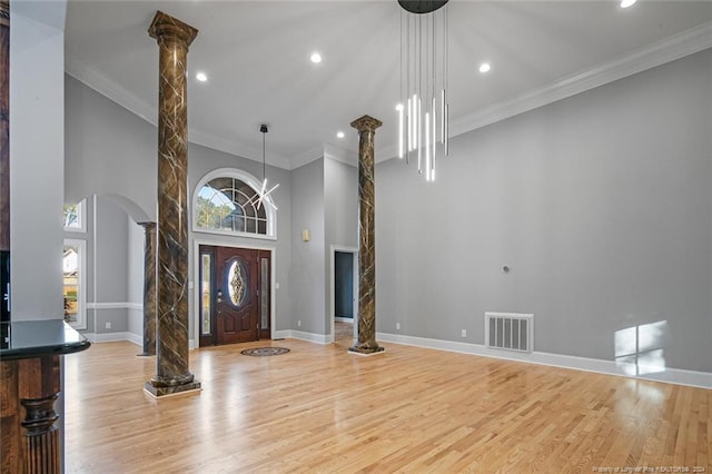 entryway with plenty of natural light, light wood-type flooring, and decorative columns