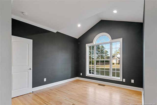 unfurnished room featuring vaulted ceiling and light wood-type flooring