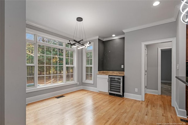 bar featuring wine cooler, a healthy amount of sunlight, hanging light fixtures, and light wood-type flooring