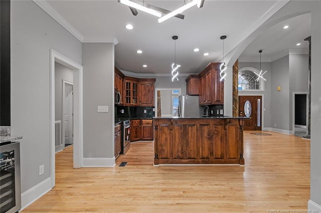 kitchen with pendant lighting, crown molding, wine cooler, light hardwood / wood-style flooring, and appliances with stainless steel finishes