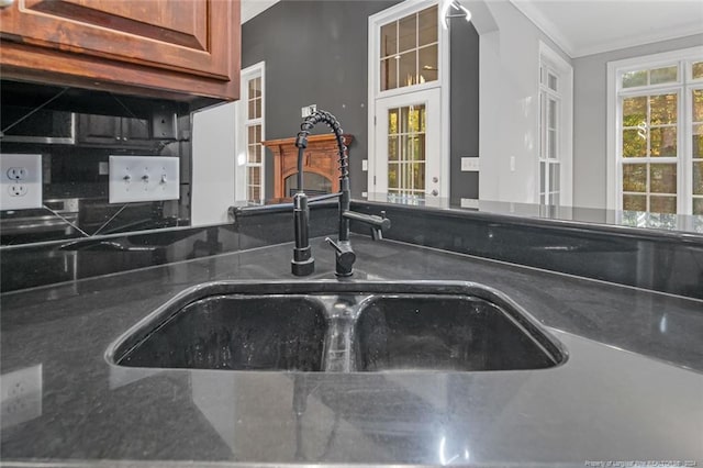 interior details featuring dark stone counters, ornamental molding, and sink
